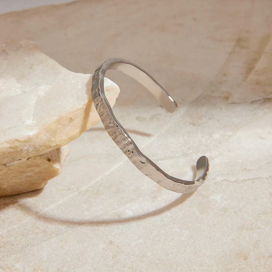 Make a bold statement with this distinctive Hammered Silver Cuff. The highly reflective, artisan texture catches the light perfectly. This cuff is adjustable, skin-friendly, and completely waterproof, crafted from 316L stainless steel with thick silver plating. Wear it solo or easily stack it for maximum impact.